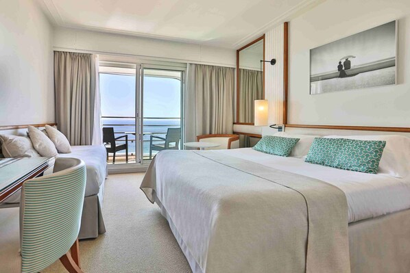 A hotel room with a bed, a desk, a chair, a small table, and a balcony with a view of the sea. - Atlantic Hotel & Spa (Les Sables-d'Olonne)