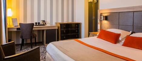 A hotel room with a bed, a desk, a chair, and a dresser.