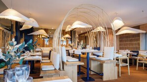 Un interior de restaurante moderno con mesas de madera, asientos acolchados blancos e iluminación colgante original.