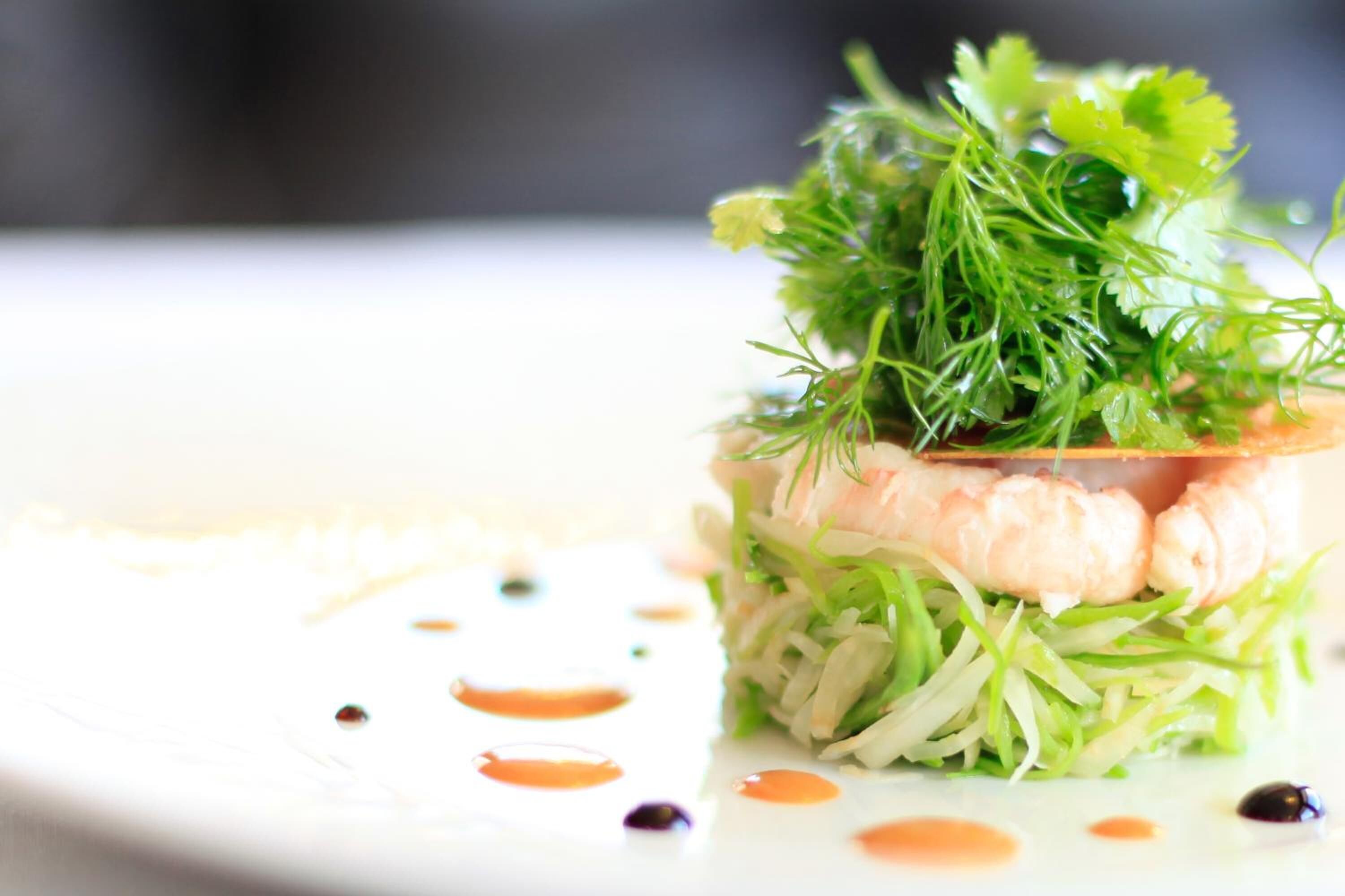 A dish with layers of ingredients and garnishes on a white plate.