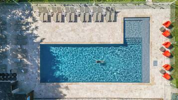 Een buitenzwembad, parasols bij het zwembad en ligstoelen