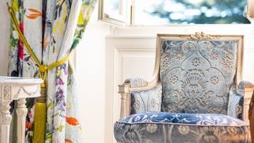 Une pièce avec des rideaux à motifs floraux, un fauteuil classique et une petite table.