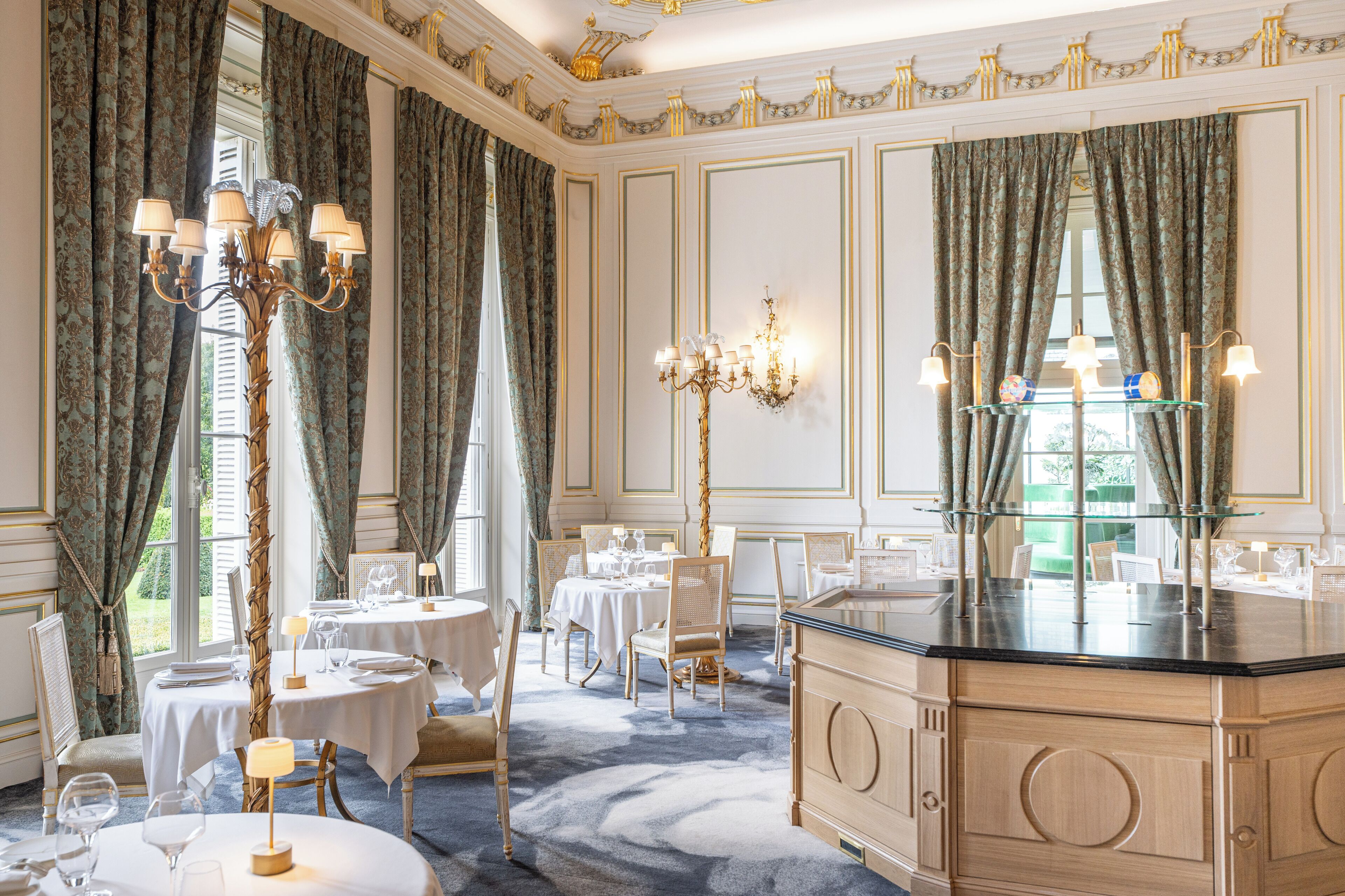 A luxurious dining room with ornate chandeliers, elegant table settings, and a classic design.