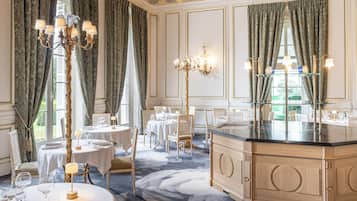 A luxurious dining room with ornate chandeliers, elegant table settings, and a classic design.
