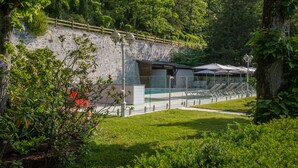 A stone wall with a wooden fence, a covered seating area, and a pathway.