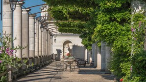 A pathway lined with stone columns and metal lamp posts, leading to an arched entrance.