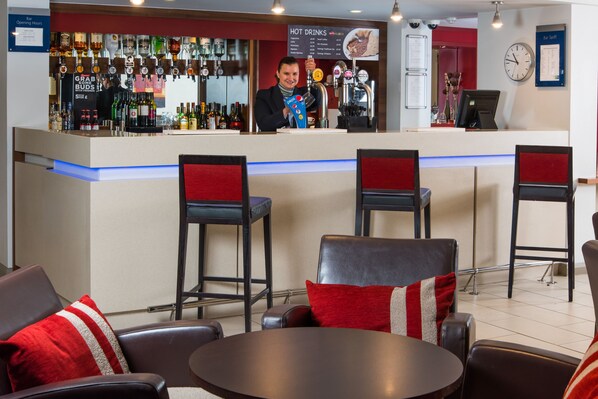A bar area with a counter, stools, and a seating area with tables and chairs. - Holiday Inn Express Bristol - Filton by IHG (Bristol)