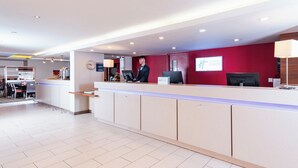Un comptoir d’accueil d’hôtel doté d’un écran numérique, d’une horloge et d’une enseigne indiquant « Holiday Inn Express ».