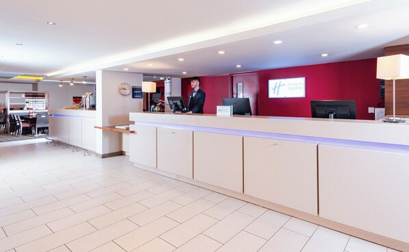 Et hotelreception med digital skærm, et ur og et skilt for Holiday Inn Express.