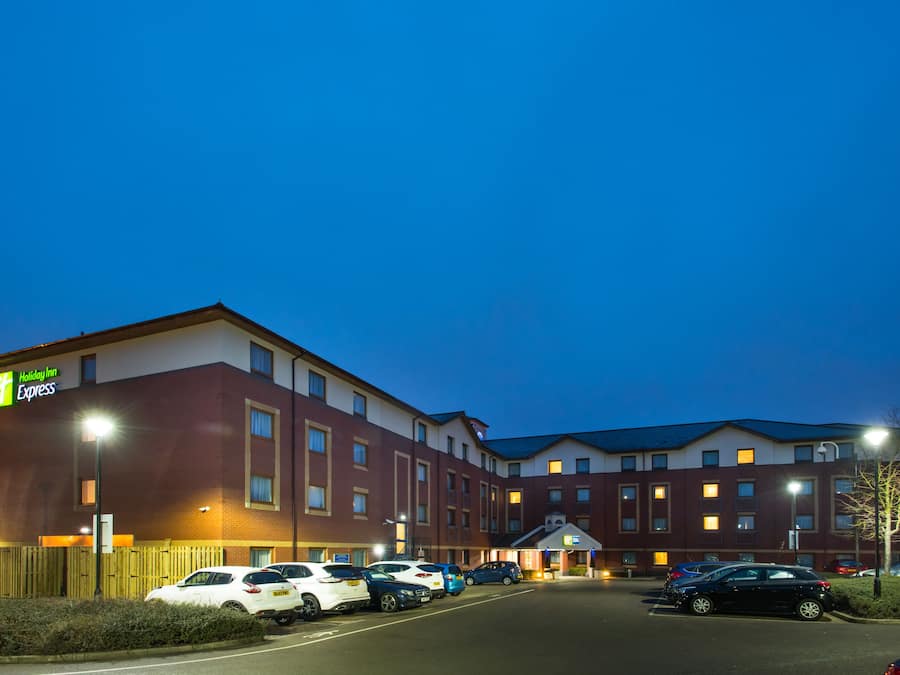 A Holiday Inn Express hotel with a parking lot and multiple cars parked in front.