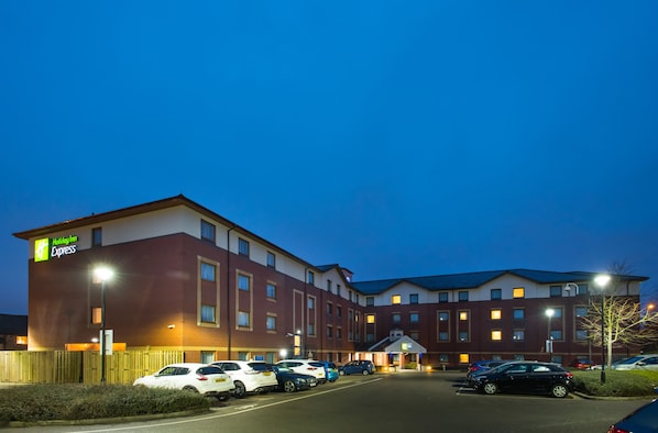 A Holiday Inn Express hotel with a parking lot and multiple cars parked in front.