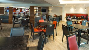 Un restaurant moderne doté de plusieurs espaces de restauration, notamment des banquettes et des tables avec des chaises.
