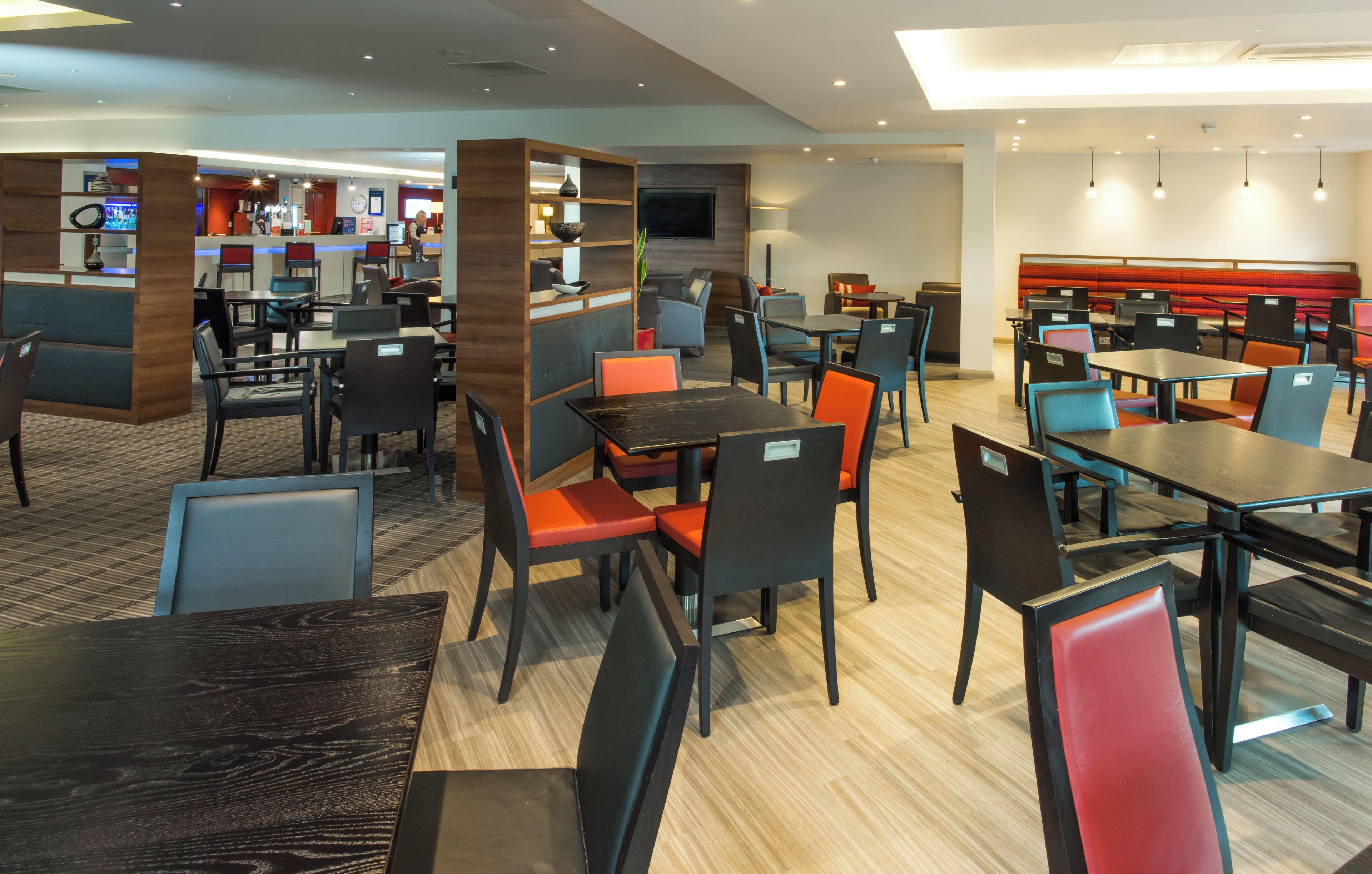Een modern restaurant met verschillende eetgedeeltes, waaronder zitjes en tafels met stoelen.