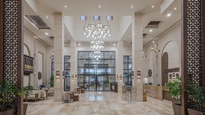 Un hall d’entrée spacieux, doté d’un sol en marbre, d’un grand lustre et d’un comptoir d’accueil.