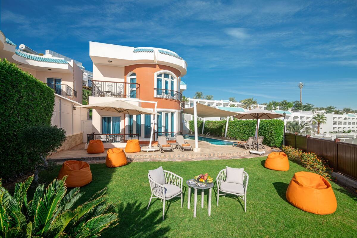 A modern house with a pool, outdoor seating, and a well-maintained lawn.