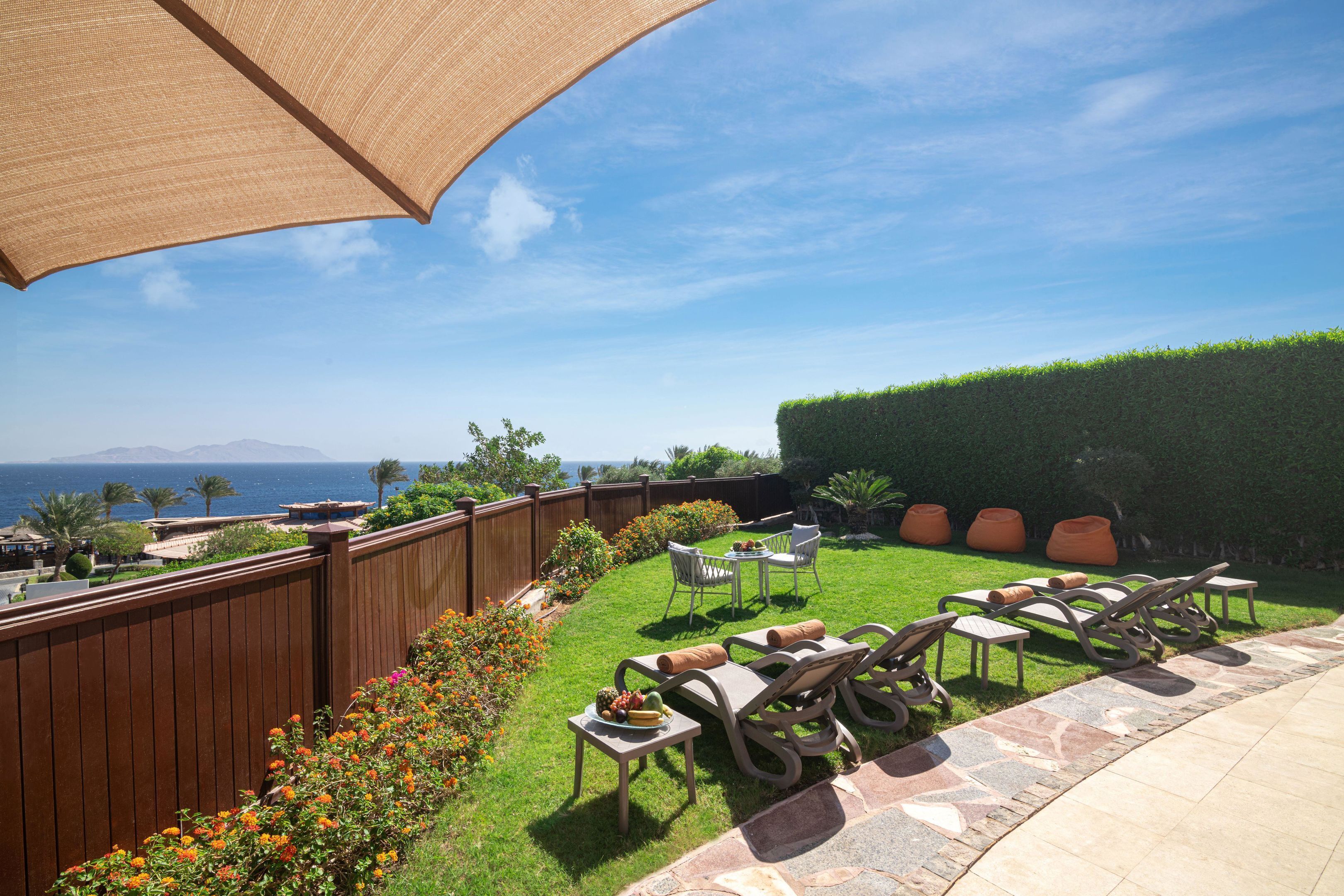 Un patio trasero con una valla de madera, un patio de piedra y mobiliario exterior, incluyendo una mesa y sillas.