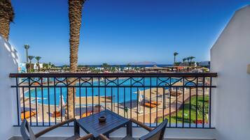 Enjoy a refreshing view of the pool area from this balcony, featuring a table and two chairs.