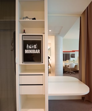 A hotel room with a minibar, a desk, and a chair.