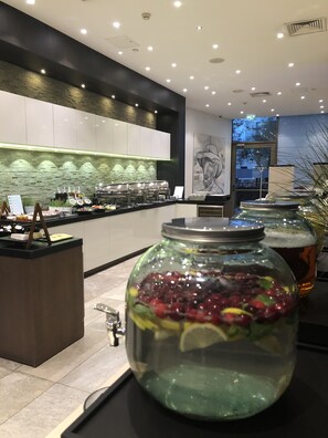 A modern kitchen area with a buffet setup, including a fruit punch dispenser and a coffee station. - Holiday Inn Vilnius by IHG (Vilnius)