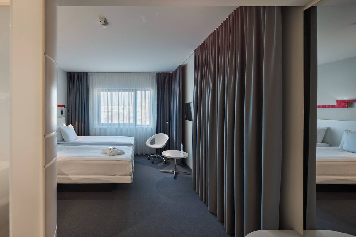 A modern hotel room with a large bed, a small round table, a chair, and a TV.