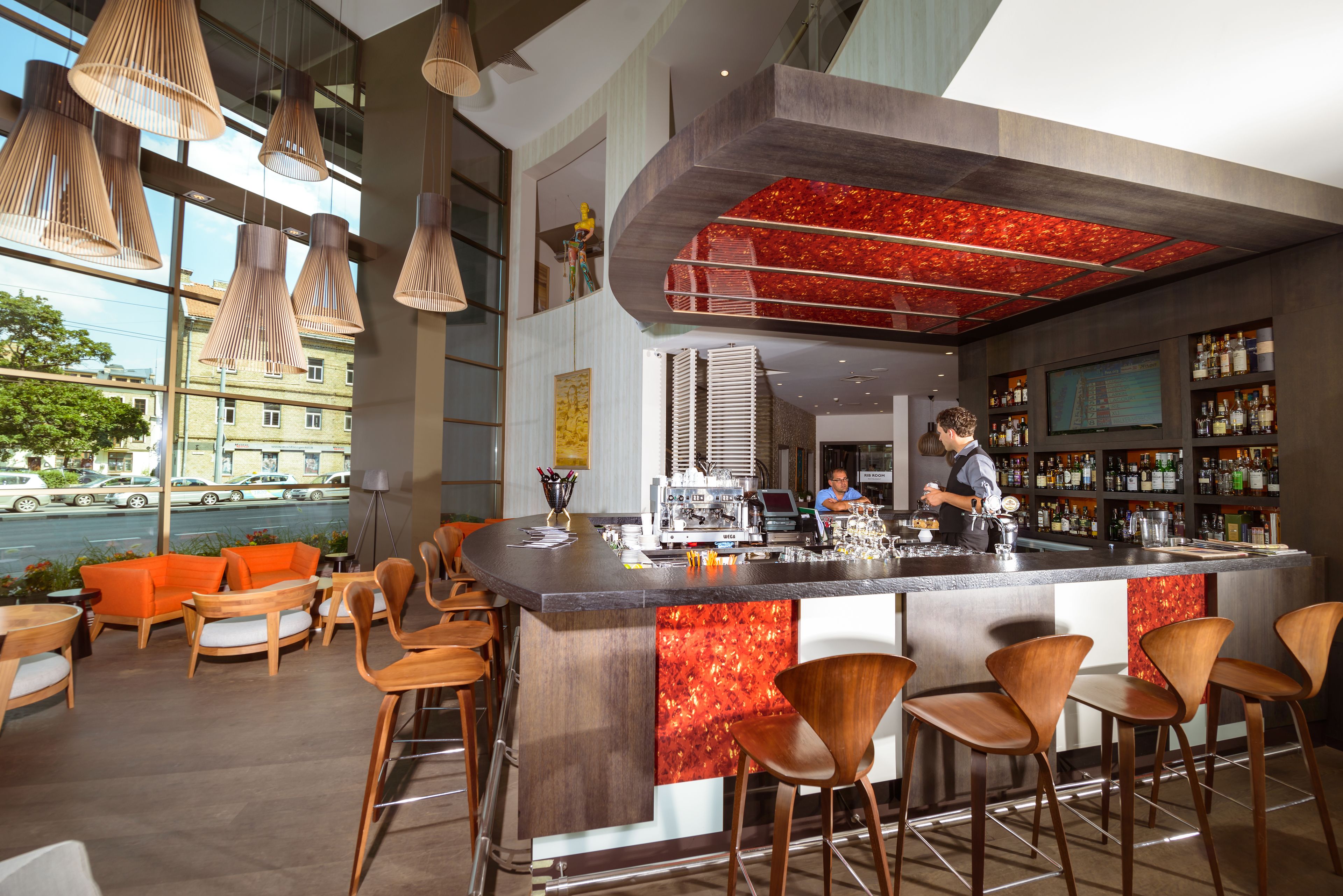 A modern bar area with a central island, bar stools, and hanging pendant lights.