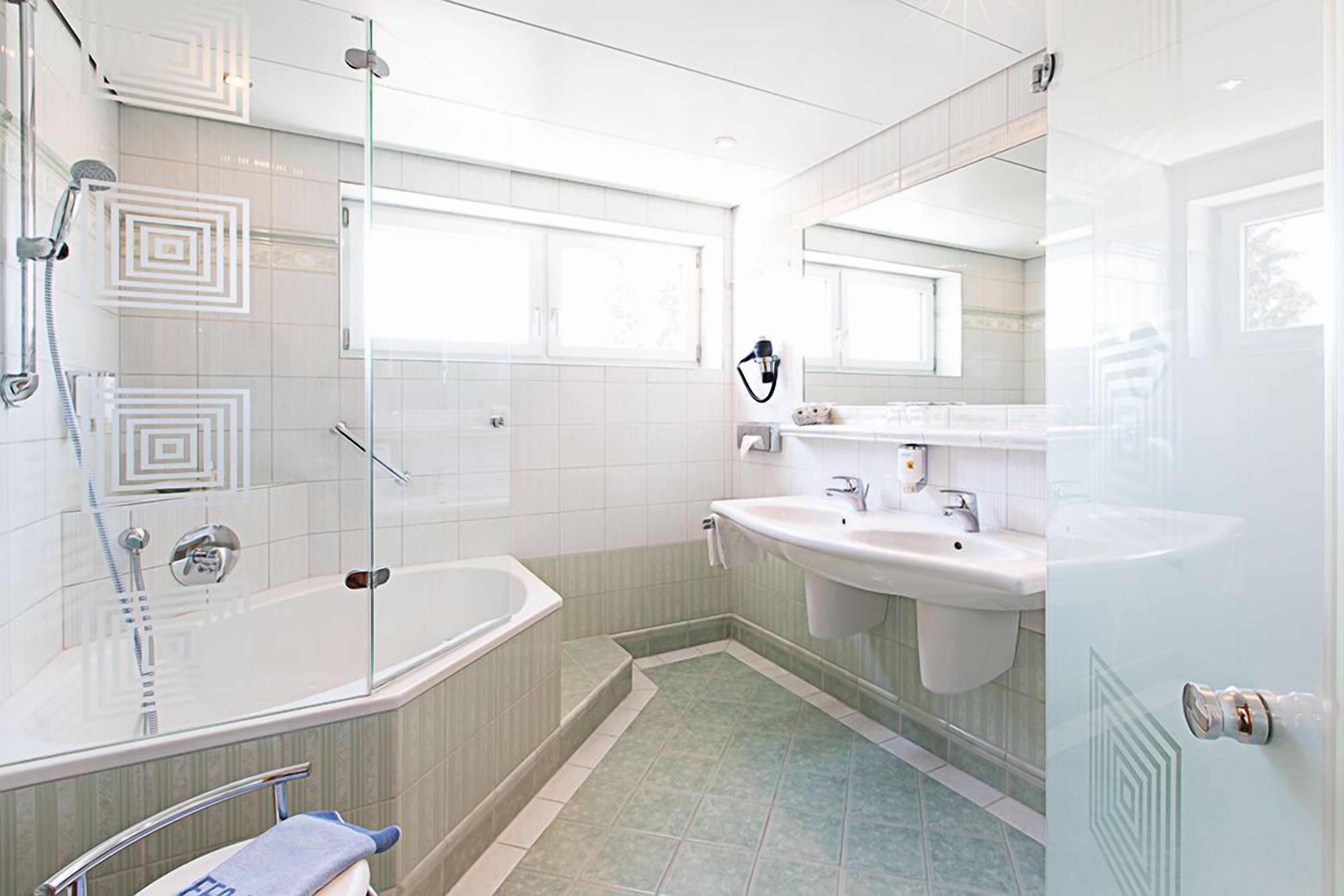 Een moderne badkamer met een glazen douchecabine, een vrijstaand bad en een wastafel met spiegel.