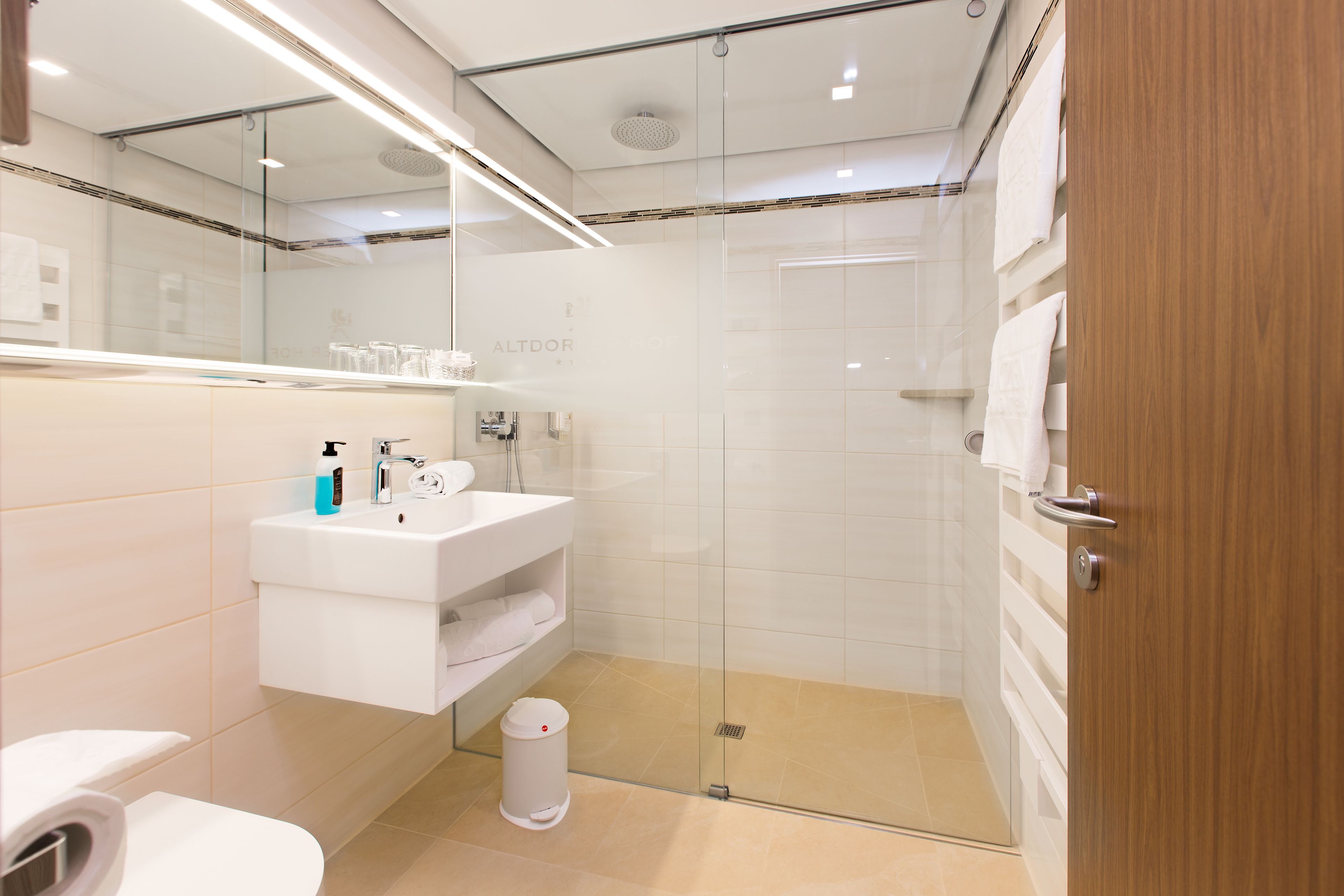 A modern bathroom with a glass-enclosed shower, a white sink, and a mirror above it.