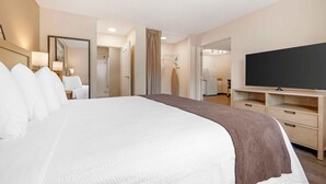 A hotel room with a large bed, a TV, a wardrobe, and a bathroom visible through an open door.