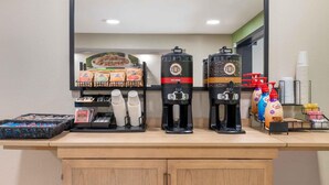 A coffee station with two coffee makers, a selection of coffee pods, and disposable cups.