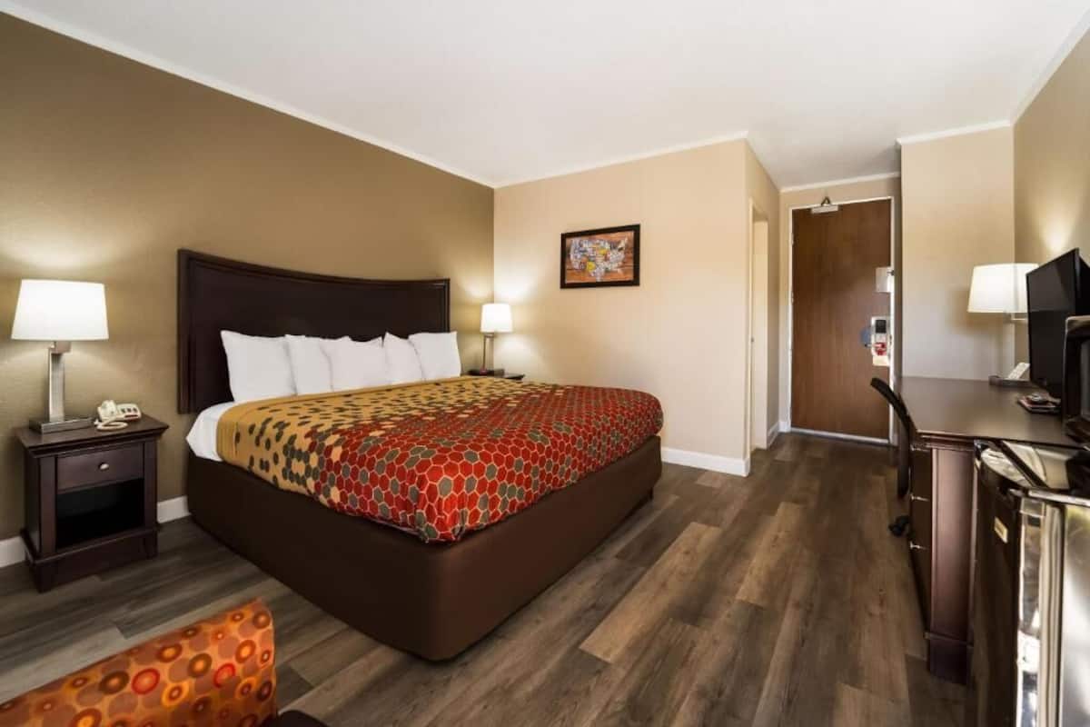 A hotel room with a large bed, bedside tables, a desk, and a television.