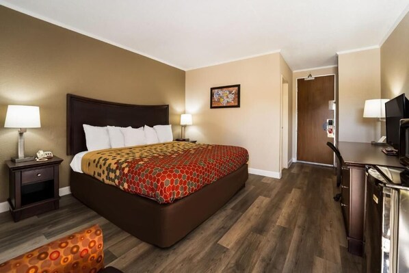A hotel room with a large bed, bedside tables, a desk, and a television.