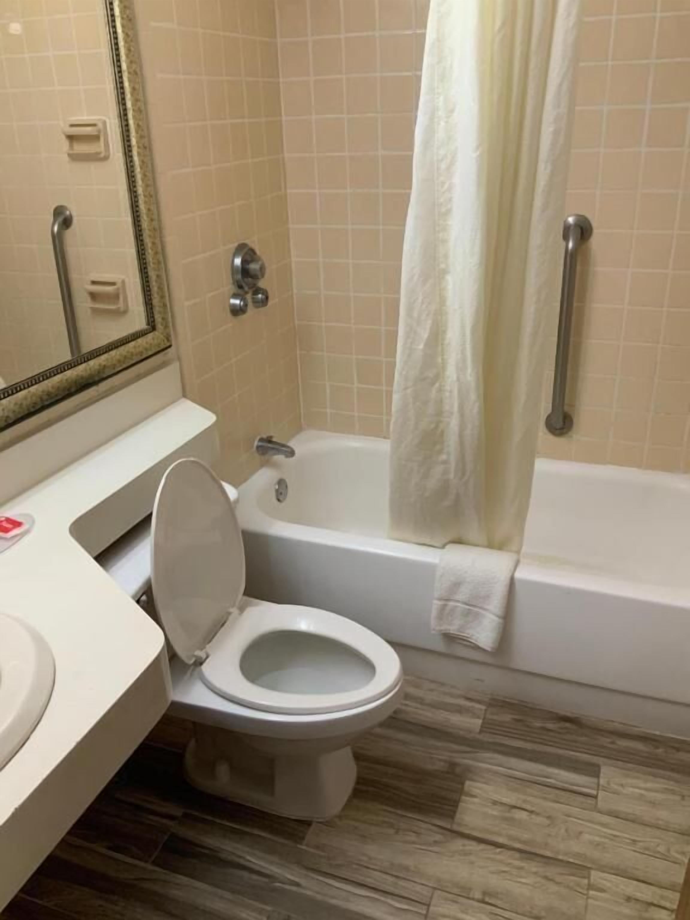A bathroom with a toilet, sink, mirror, shower, and bathtub.