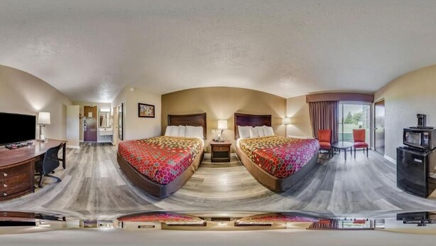 Habitación de hotel con dos camas, un escritorio, un televisor y un comedor con mesa y sillas.
