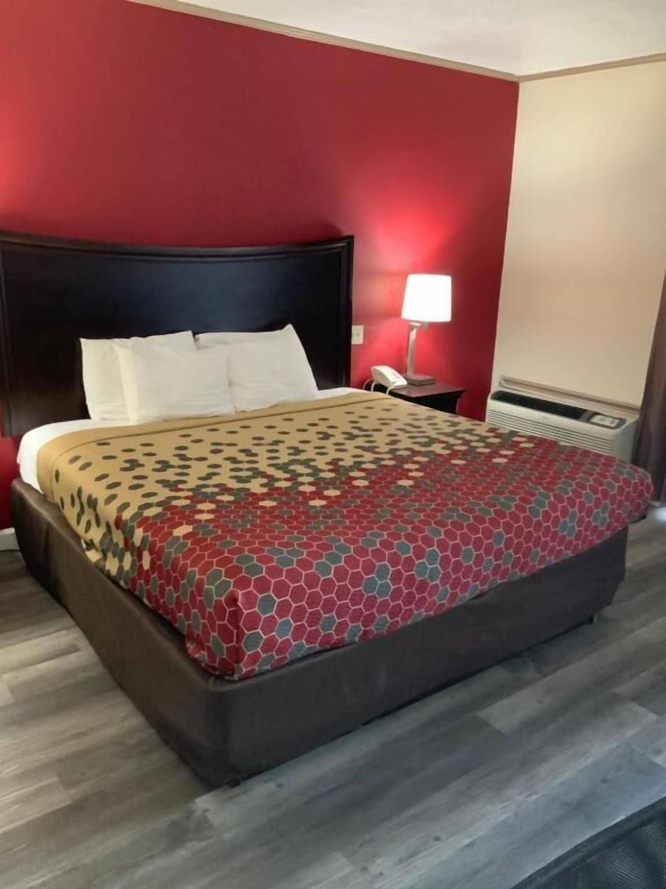 Een hotelkamer met een groot bed, een nachtkastje, een lamp en een heater.
