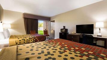 Ein Hotelzimmer mit zwei Betten, einem Schreibtisch, einem Fernseher und einem Sessel.