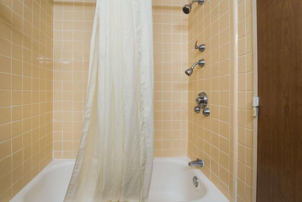 A bathroom with a bathtub, a showerhead, and a curtain.