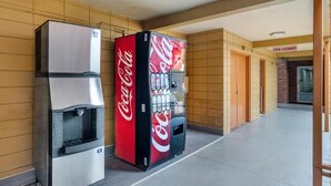 Máquina expendedora y dispensador de agua en un pasillo con paredes de azulejos y un cartel de lavandería automática.