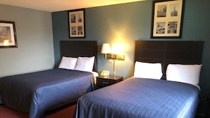 A hotel room with two beds, a nightstand with a lamp, and framed pictures on the wall. - Latham Inn (Latham)