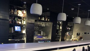 A bar area with a long counter, multiple bar stools, and shelves stocked with bottles and glasses. - Latham Inn (Latham)