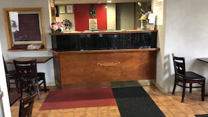 A reception area with a wooden counter, a red wall, and a tiled floor. - Latham Inn (Latham)