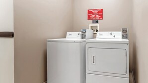 Een wasserette met twee Whirlpool wasmachines en een bordje met de openingstijden en stilteperiode voor gasten.