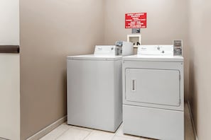 A laundry facility with two Whirlpool washers and a sign indicating guest laundry hours and quiet time.