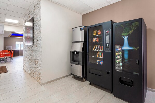 En automat og et køleskab i et rum med en stenvæg og flisegulv.