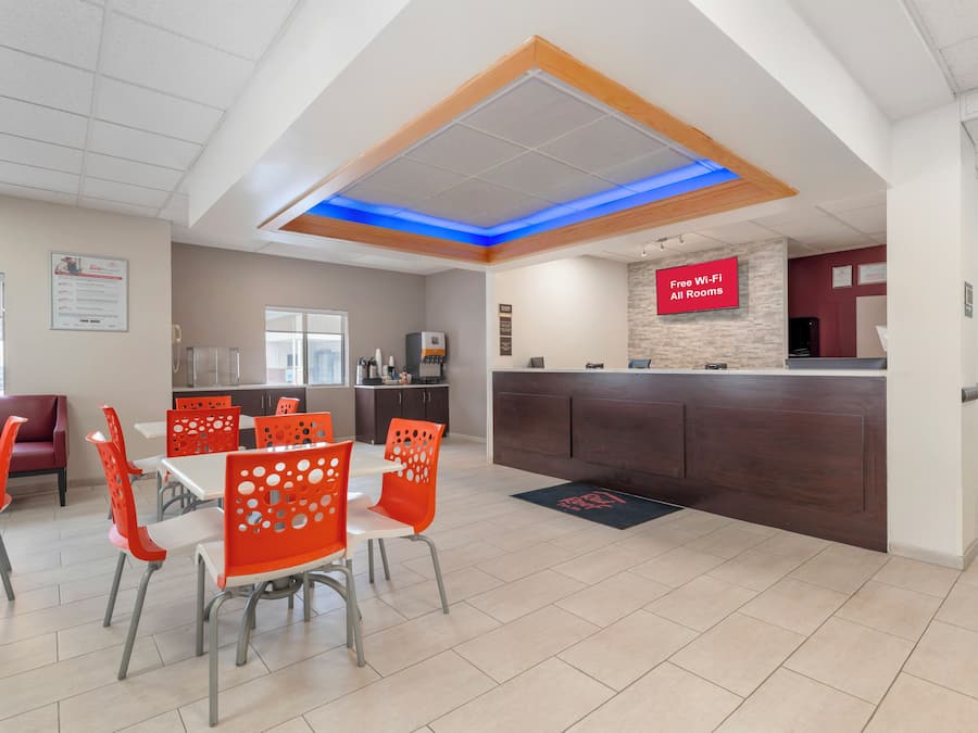 A modern restaurant with a counter, red chairs, and a sign indicating free Wi-Fi.