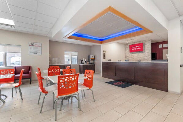 A modern restaurant with a counter, red chairs, and a sign indicating free Wi-Fi.
