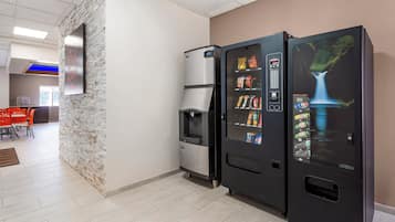 Máquina expendedora con aperitivos y bebidas, un dispensador de agua y un cartel en la pared.