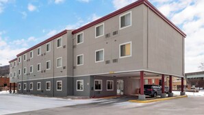 Um hotel com vários andares, teto plano, diversas janelas e área de estacionamento coberta.
