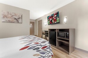 Habitación de hotel con cama, televisor, microondas y escritorio.