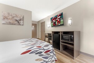 Habitación de hotel con cama, televisor, microondas y escritorio.