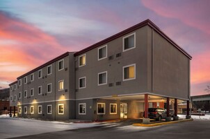 Un hotel de varios pisos con fachada plana, numerosas ventanas y un estacionamiento techado.
